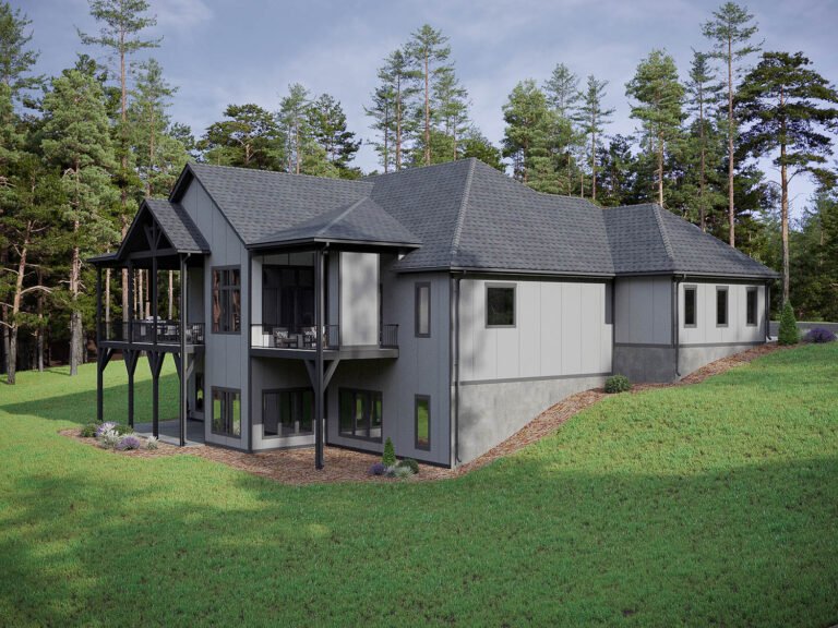 A modern, two-story house with a gray exterior and a multi-gabled roof sits on a grassy lawn surrounded by a lush pine forest. The house features large windows, a wraparound porch, and a raised deck, creating a harmonious blend of indoor and outdoor living spaces. The overall design and integration with the natural landscape suggest a comfortable, secluded retreat in a peaceful, wooded setting.