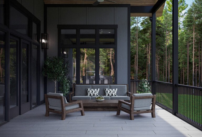 A modern outdoor living space with a covered patio, featuring a plush gray sectional sofa, wooden armchairs, and a low wooden coffee table. The patio is surrounded by a lush forest, with large windows providing a panoramic view of the natural surroundings. The dark, sleek exterior of the home creates a striking contrast with the verdant landscape, creating a serene and inviting atmosphere.