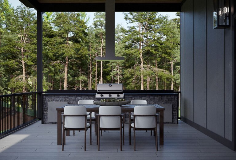 A modern outdoor kitchen and dining area with a stone fireplace, gas grill, and wooden dining table and chairs. The space is surrounded by a lush, forested landscape visible through the large windows, creating a serene and natural ambiance.