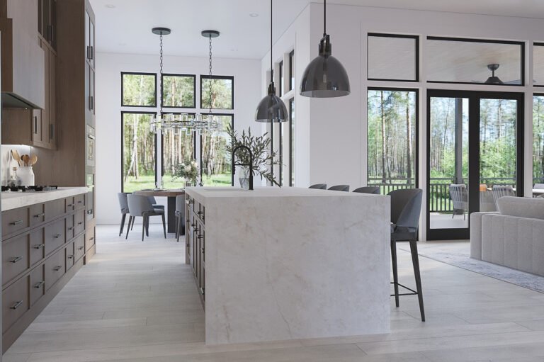 A modern, open-concept kitchen with a large, white marble island, sleek gray cabinetry, and pendant lighting fixtures. The space features floor-to-ceiling windows overlooking a lush, forested landscape, creating a bright and airy atmosphere.